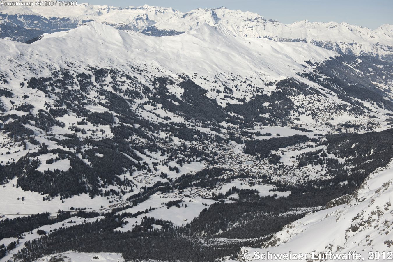 Lenzerheide im Bildzentrum, Blick nordwärts über das Eisfeld zum zugefrorenen Heidsee. Skigebiete links: Piz Scalottas, Alp Lavoz, Piz Raschil, Stätzerhorn. Bildmitte rechts: Valbella